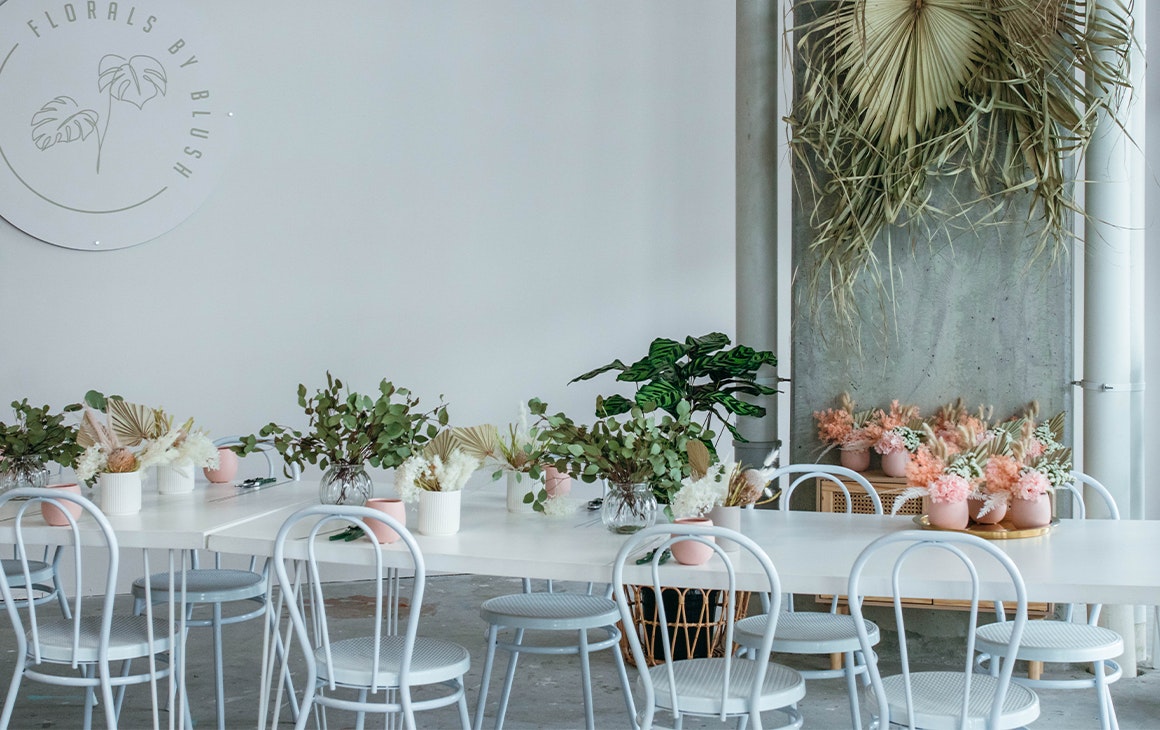 Long White table decorated with pink and white pot plants at Florals By Blush